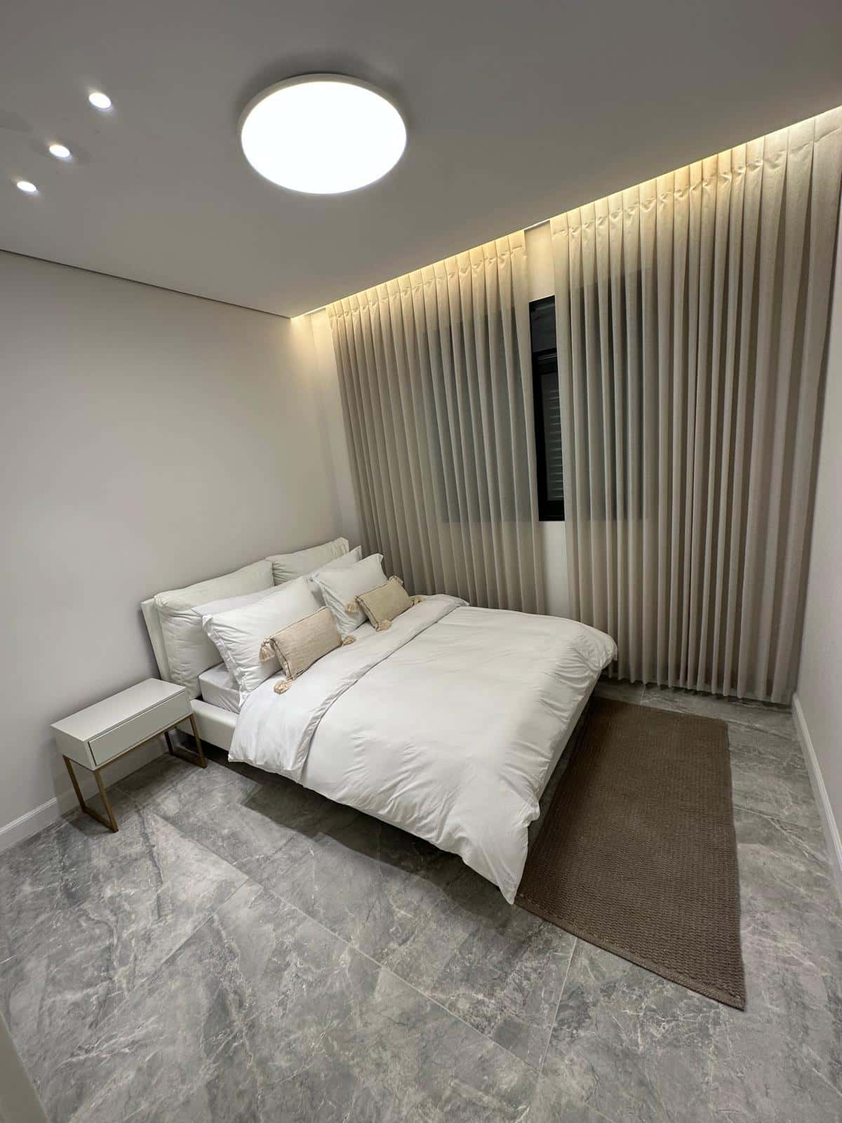 A finished bedroom with a cove-lit ceiling, smooth walls and clean trim