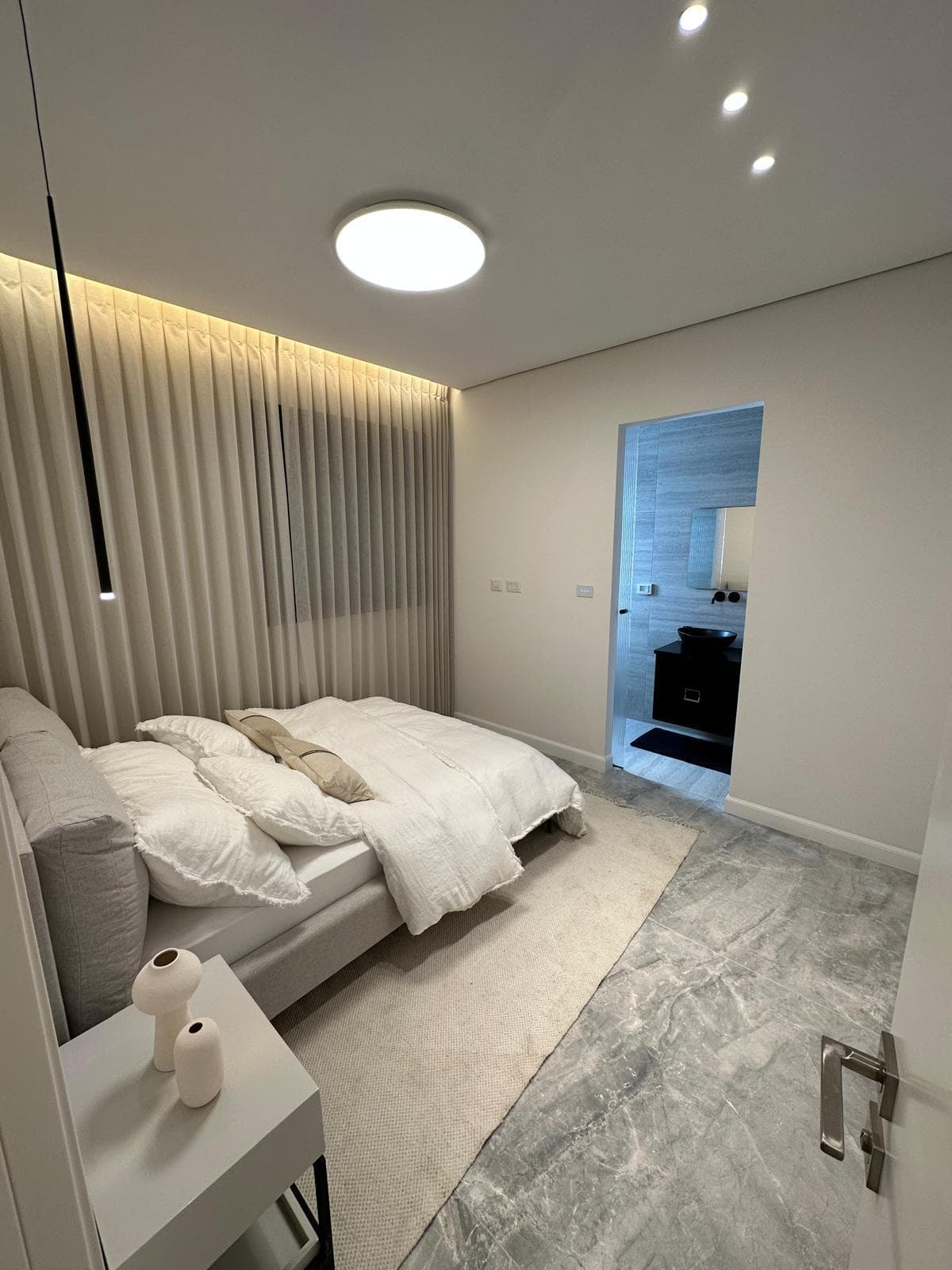 Finished bedroom with cove lighting and an adjoining ensuite