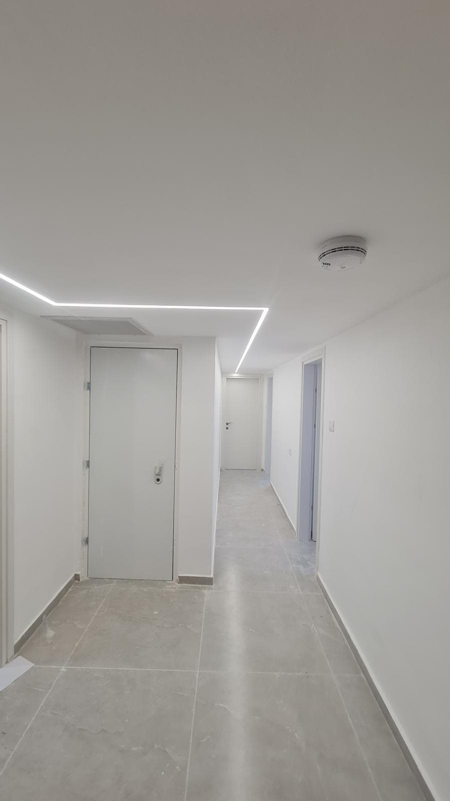 Bright corridor with recessed LED ceiling lighting and clean finished doors